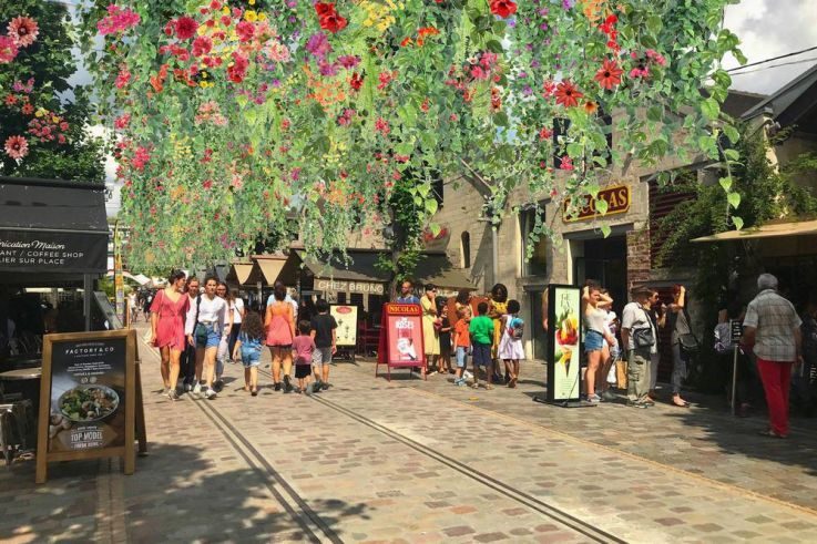 Paris secret : sons, odeurs et gestes d'un quartier. 2 Rue pavée de Bercy Village à Paris, animée de passants et de terrasses : expérience immersive dans le quartier.